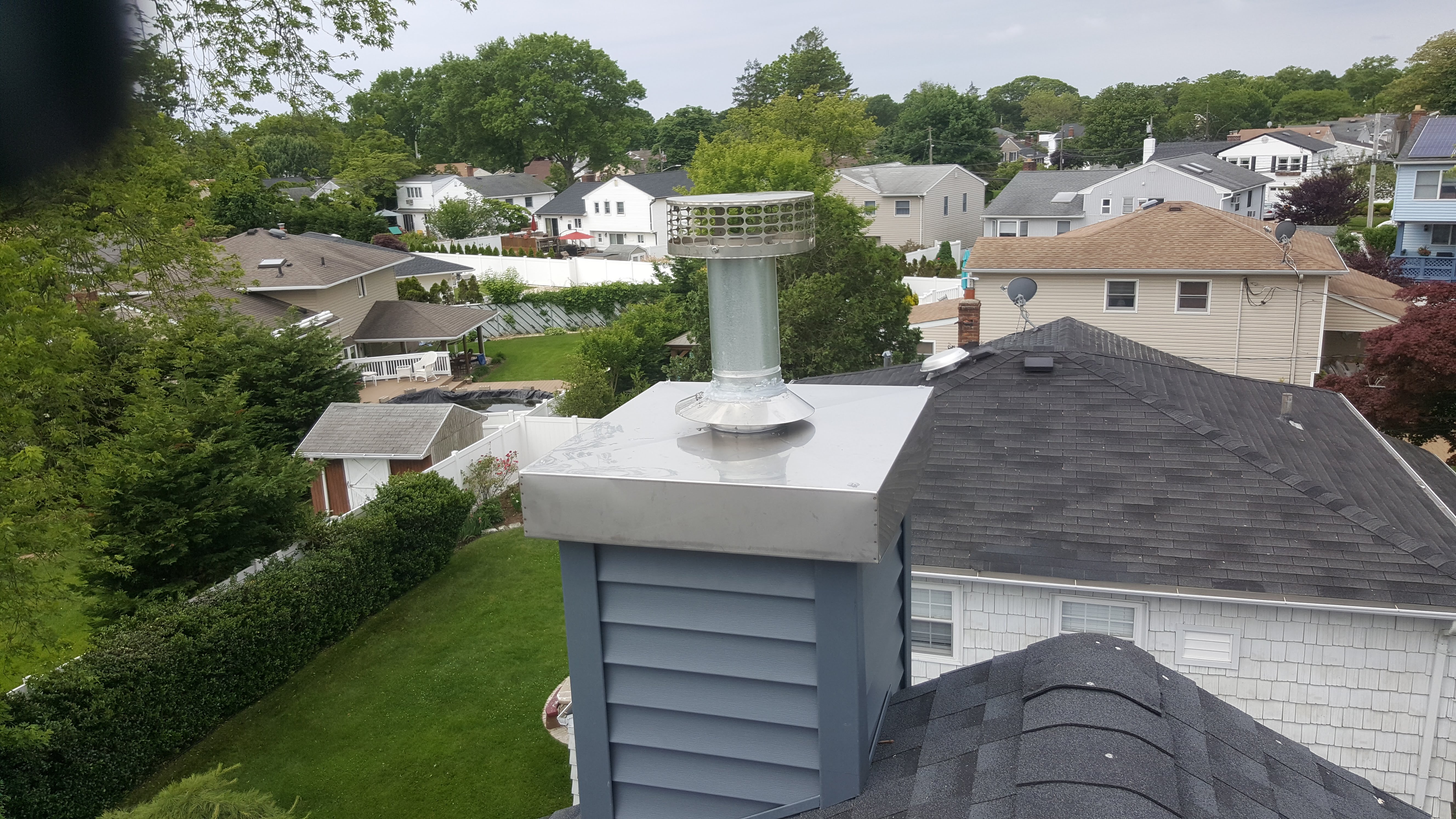 A TEAM OF PROFESSIONALS INSTALLING A NEW CHASE COVER ON A CHIMNEY IN FARMINGDALE