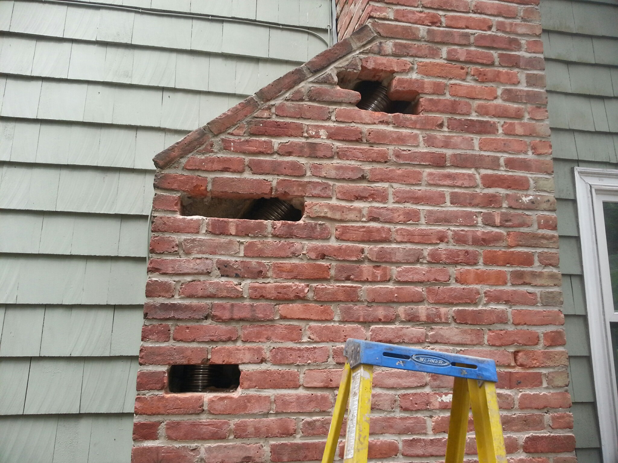A NEW STAINLESS STEEL CHIMNEY LINER BEING LOWERED INTO THE CHIMNEY FLUE IN FARMINGDALE