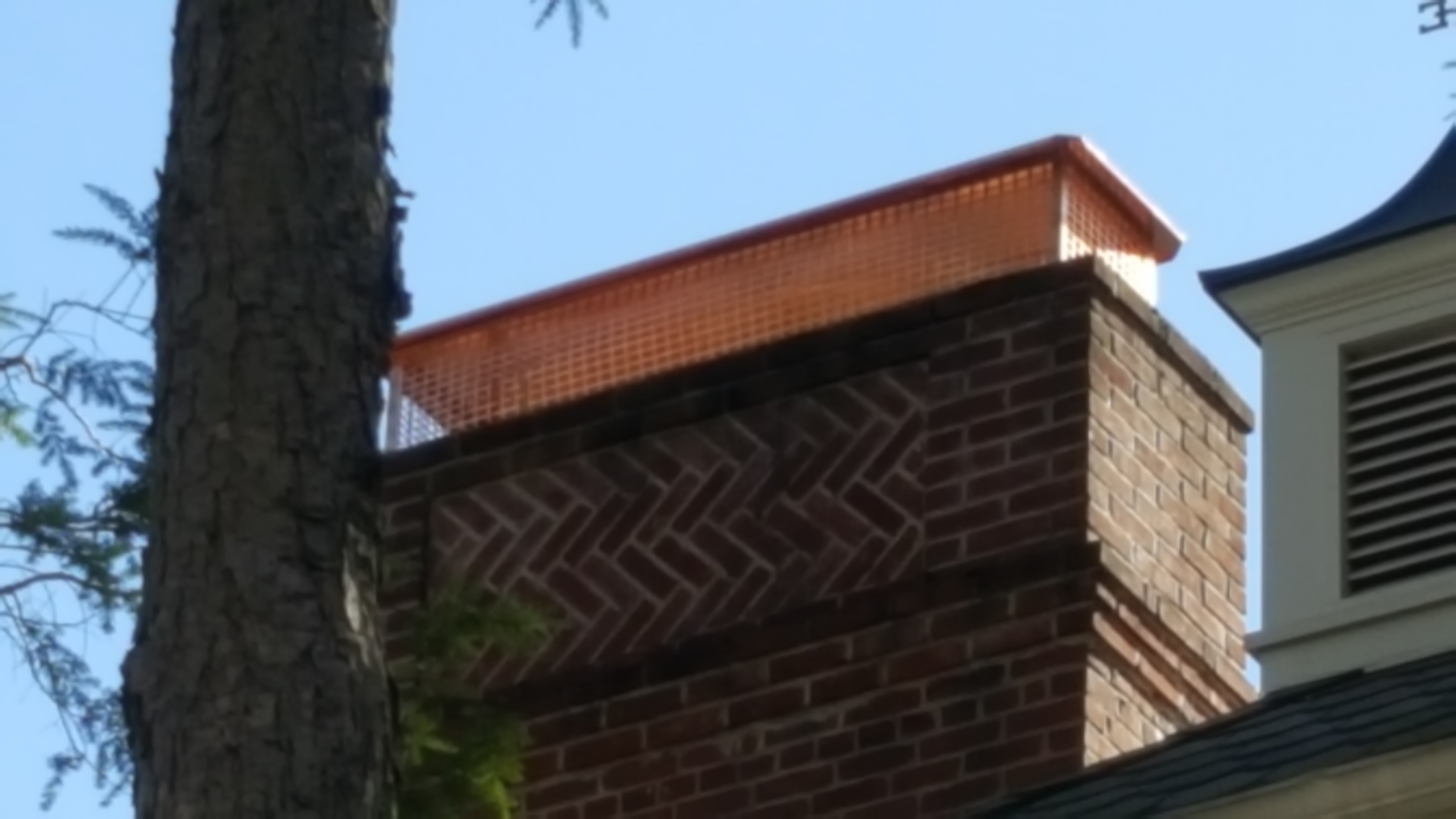 A TECHNICIAN USING A SPRAYER TO APPLY A CHIMNEY WATERPROOFING PRODUCT IN FARMINGDALE